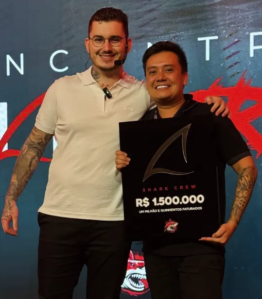 Caê Nonaka segurando placa de premiação de 1,5 milhão